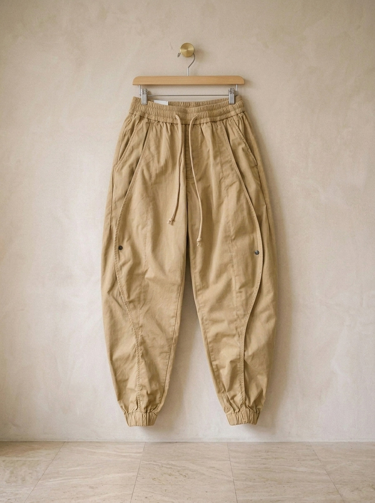 Caqui | Calça jogger de algodão Guimarães caqui – peça sozinha, no cabide de madeira