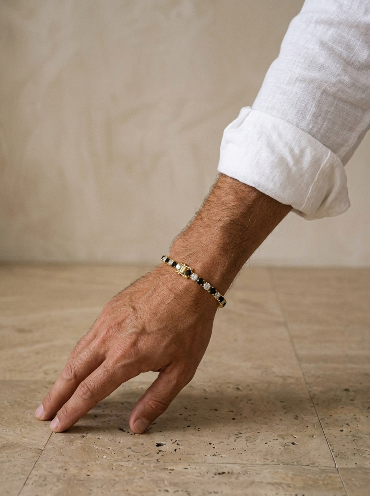 Dourado | Pulseira riviera de moissanite preto e branco Syros – no pulso, com punho de camisa de linho branca
