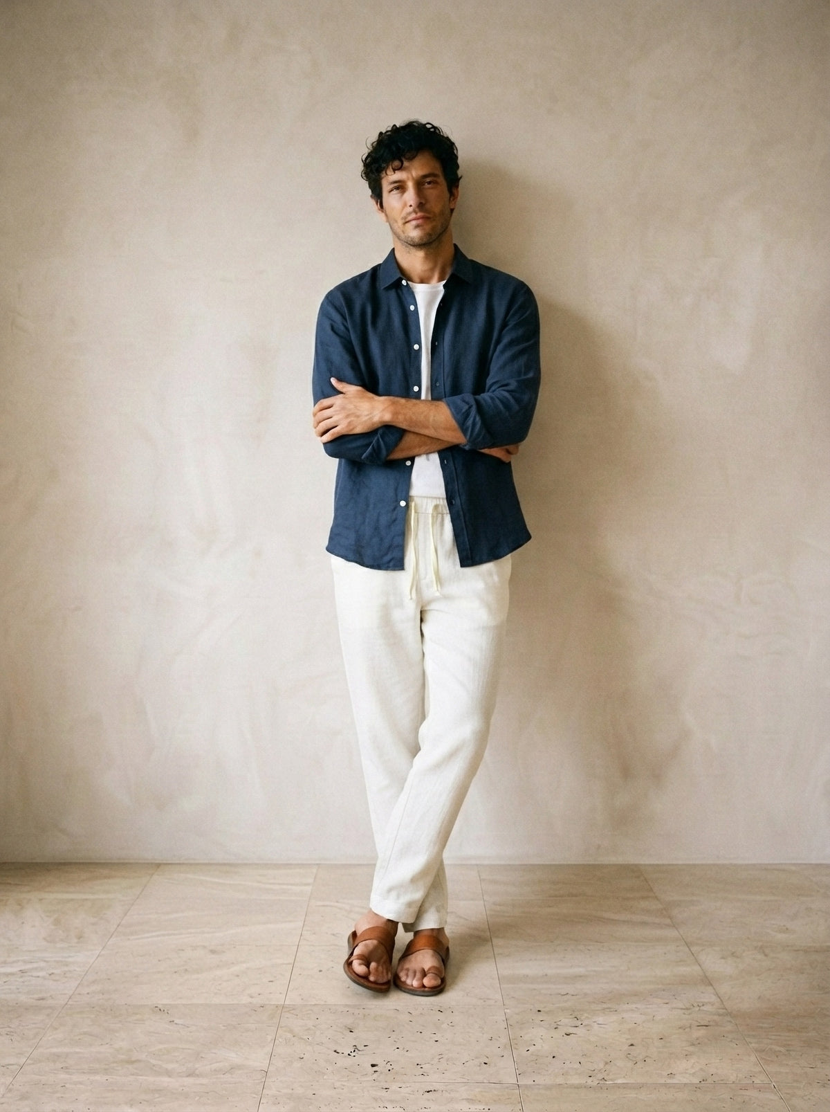 Camisa marinho, calça off-white | Conjunto camisa e calça de linho Balchik – modelo encostado na parede
