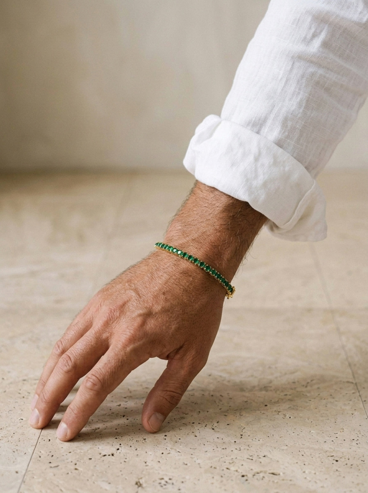 Dourado | Pulseira riviera de zircônia verde Giglio – no pulso, com punho de camisa de linho branca