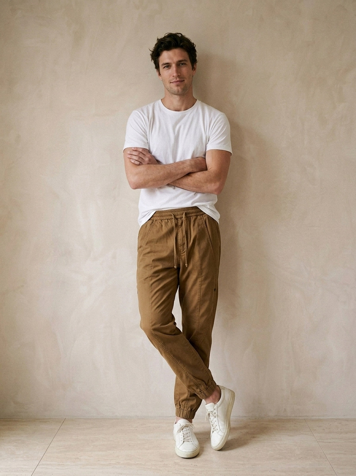 Marrom | Calça jogger de algodão Guimarães marrom – modelo encostado na parede