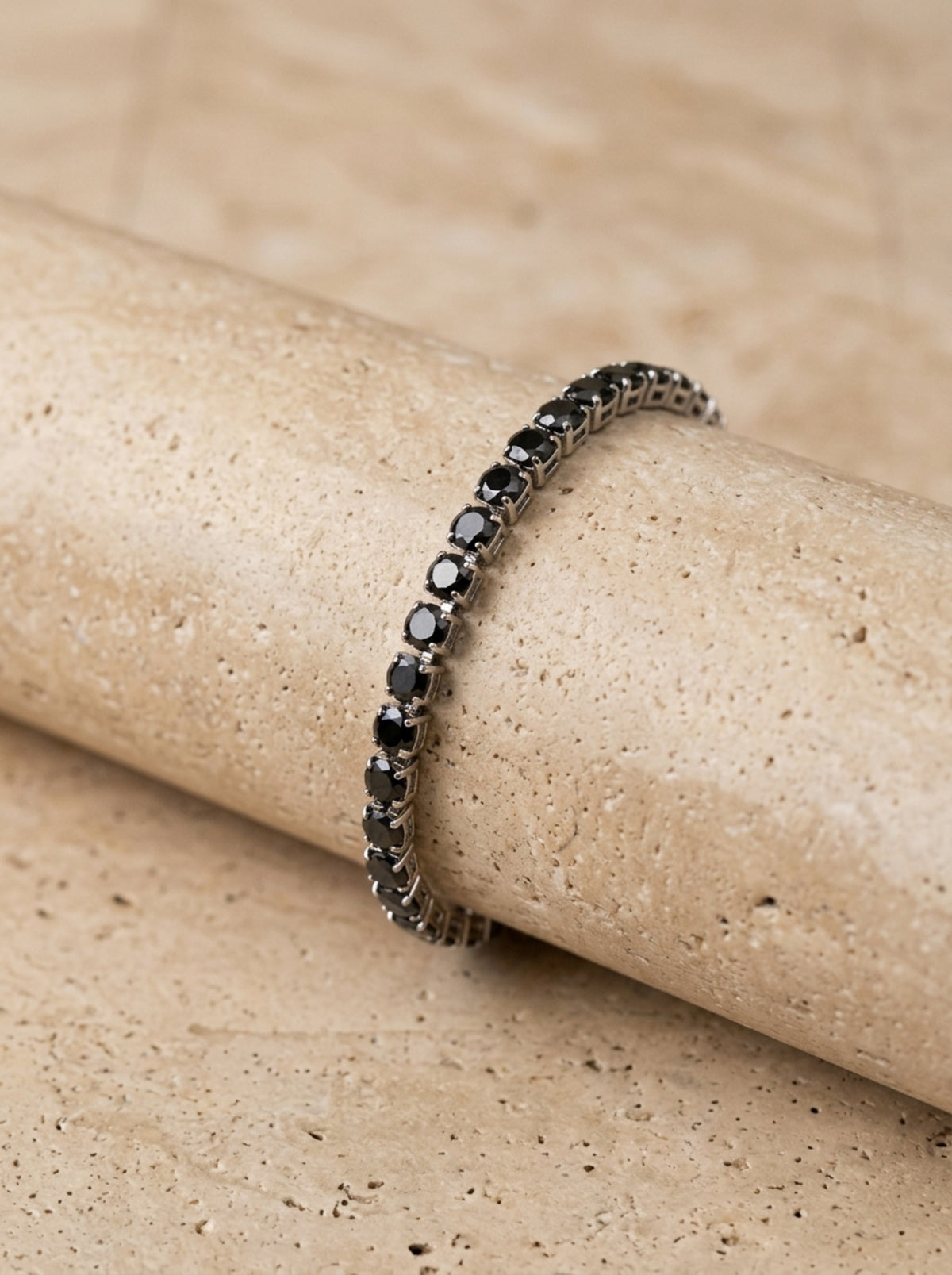 Zircônia negra | Pulseira riviera de zircônia negra Ravenna – foto real, pulseira apoiada em relevo de pedra