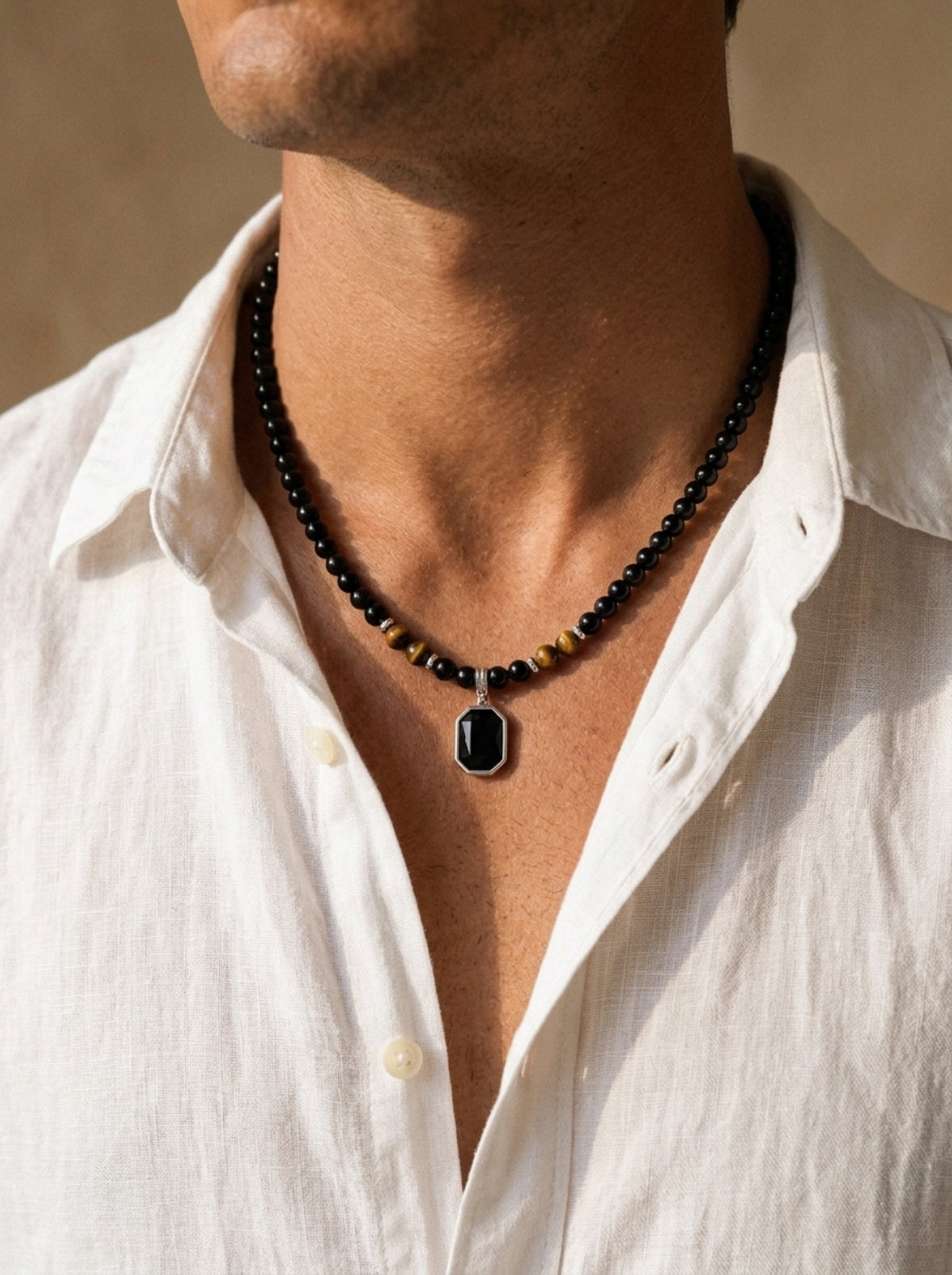 Preto | Colar de contas pretas com pingente Scilla – no pescoço, com camisa de linho branca de gola aberta
