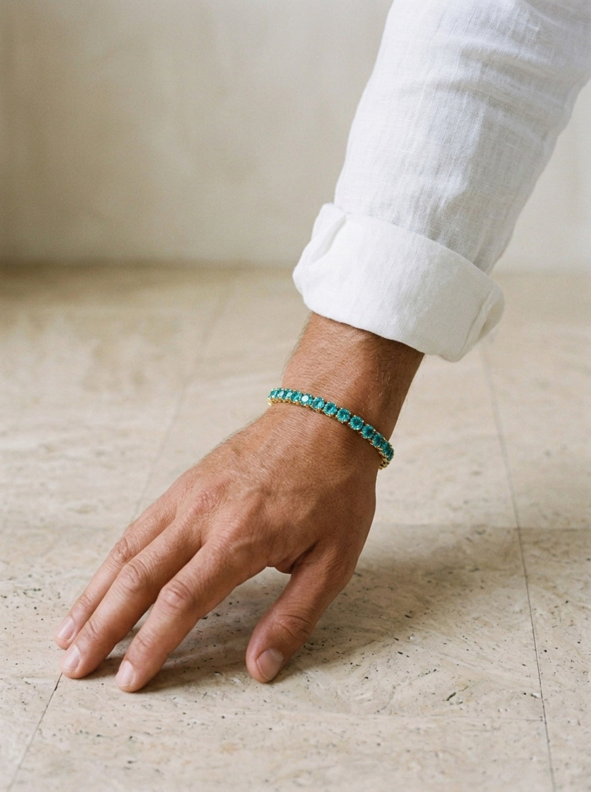 Dourado | Pulseira riviera de zircônia azul Paraíba Tinos – no pulso, com punho de camisa de linho branca